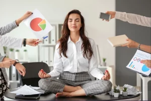 a woman sitting cross legged on her desk meditating